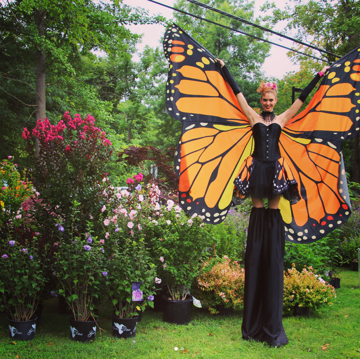 woman on stilts dressed as butterfly at outdoor corporate event